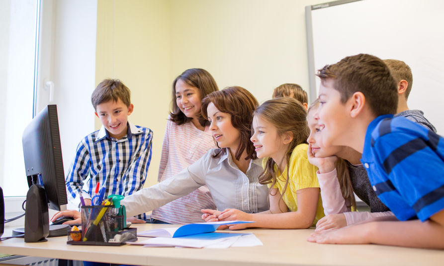 Image of female teacher and students at a computer